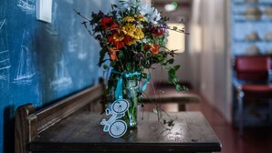 Un banco de madera con un jarrón de flores y una bicicleta decorativa.