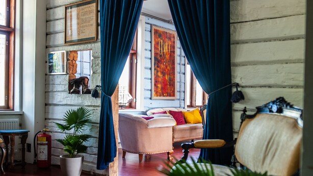Una habitación con paredes de madera, un sofá, una silla y una ventana con cortinas.