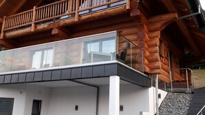 A modern log cabin with a balcony, a staircase leading to the entrance, and a flat roof. - Kanadisches Naturstamm-blockhaus (Linden)