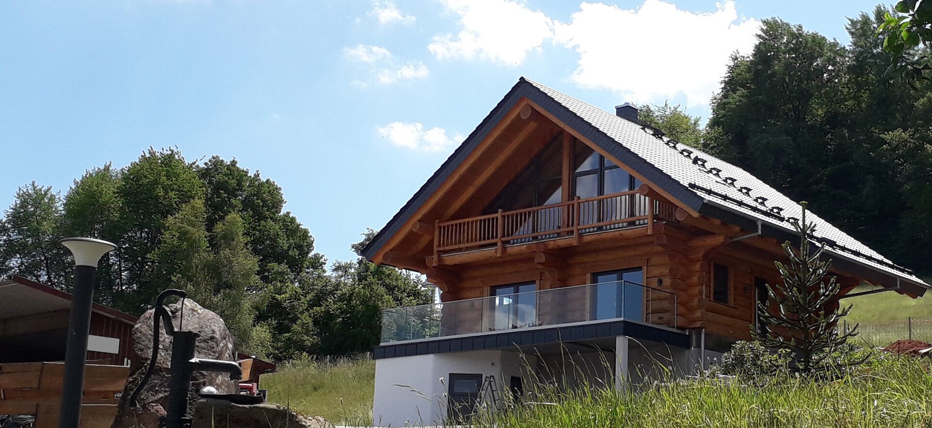 A wooden cabin with a balcony, a small attached structure, and a clear sky.
