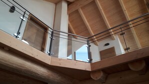 A wooden interior with a glass railing on a balcony. - Kanadisches Naturstamm-blockhaus (Linden)