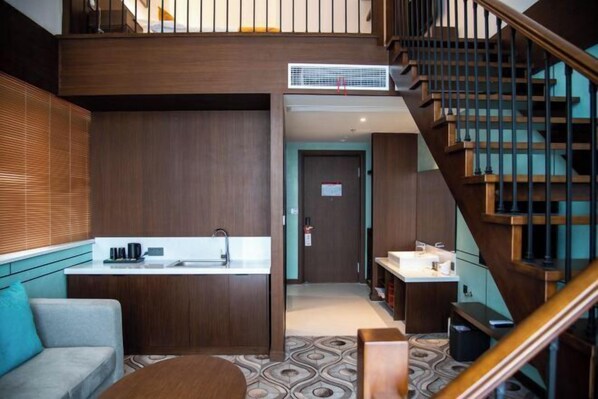 Una habitación de hotel moderna con kitchenette, un sofá, una escalera y un suelo estampado.
