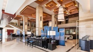 A modern lobby with a reception desk, seating area, and a staircase. - LOUNGE GROUP (Suzhou)