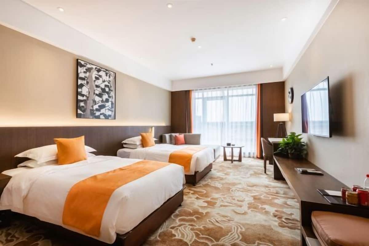 Une chambre d’hôtel avec deux lits, un bureau, une télévision et une grande fenêtre.