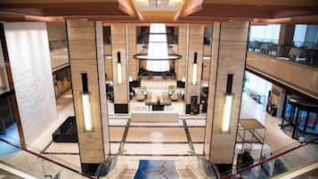 A high-ceiling atrium with a central chandelier, a seating area, and a view of the lower level.