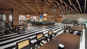 A spacious indoor area with tables and chairs arranged in a casual layout, featuring a distinctive wavy ceiling design and a striped floor pattern. - LOUNGE GROUP (Suzhou)