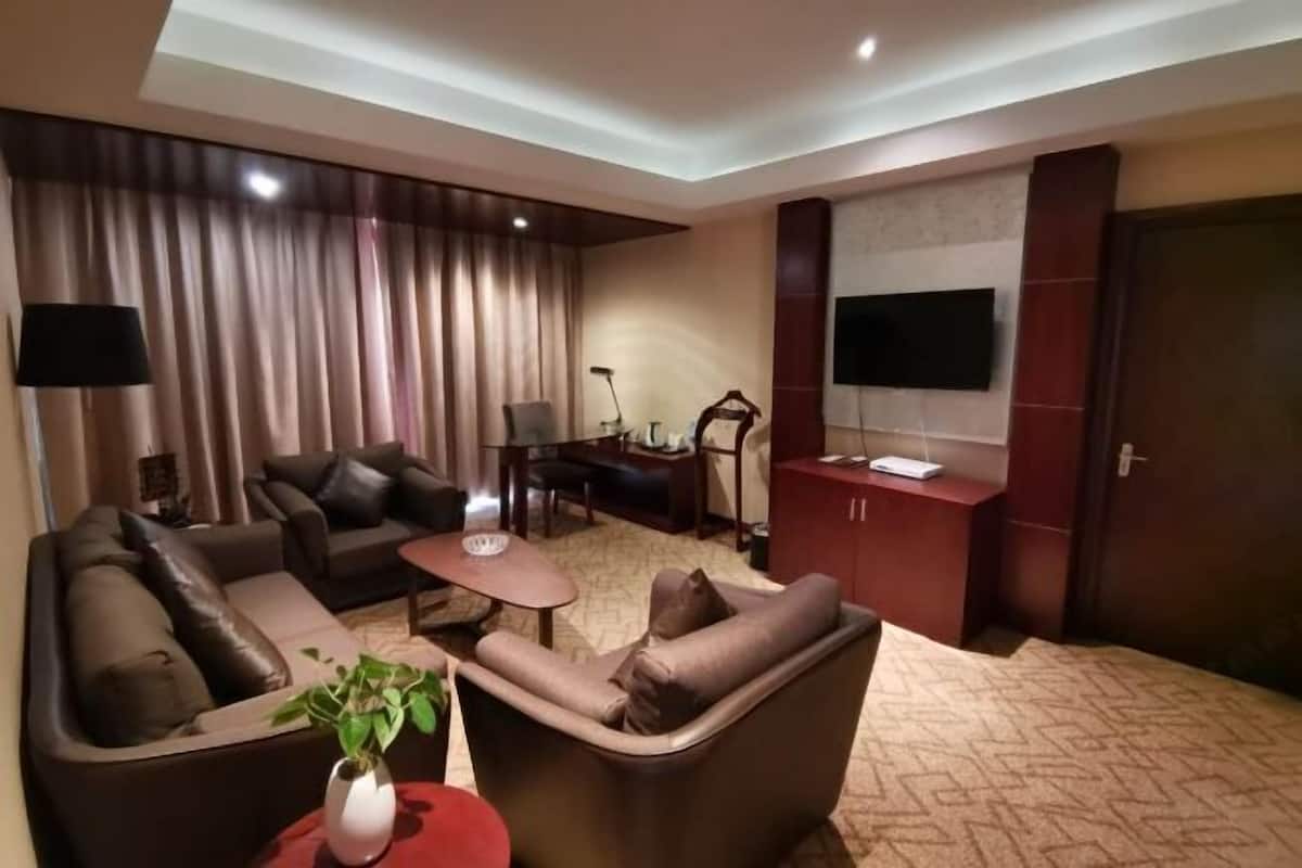 Un salon moderne comprenant un canapé, un fauteuil, une table basse et un téléviseur à écran plat fixé au mur.