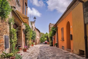 A narrow cobblestone street lined with historic buildings, some with visible brickwork and others with painted facades. - Villa Candida - Relaxation in the hills, just a stone's throw from the sea (Poggio Torriana)