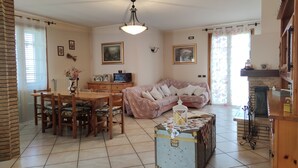 Una sala de estar acogedora con comedor, sofá, maleta antigua y chimenea.