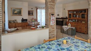 Un comedor con una mesa dispuesta para dos, una chimenea y un armario de madera con diversos objetos.
