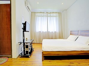 A hotel room with a wooden bed, a TV on a stand, and a window with curtains. - OYO 90597 Delightful Holiday Inn (Ranau)