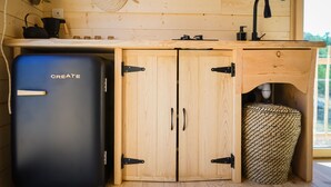 Een praktische keuken met houten kastjes, een spoelbak en een zwarte koelkast.