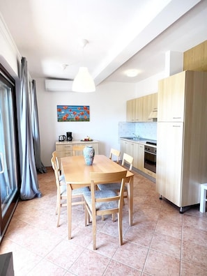 A modern kitchen with wooden cabinets, a dining table with chairs, and a painting on the wall. - Apartment Tulipano (Funtana)