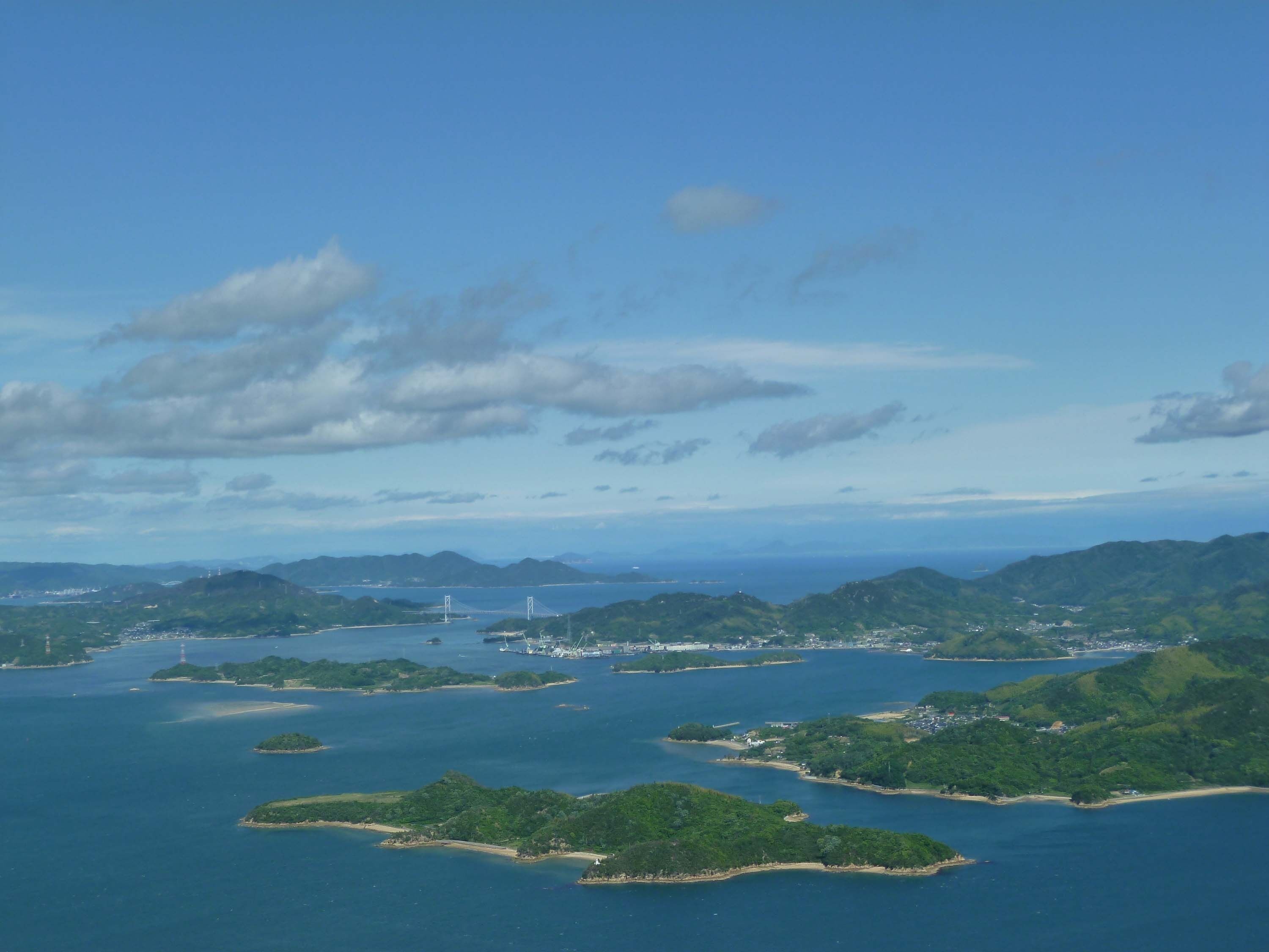 An aerial view of a coastal area with multiple islands, a bridge, and a port.