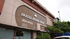 Een hotel genaamd HOTEL PEARL VIEW met een moderne gevel en borden in verschillende talen.