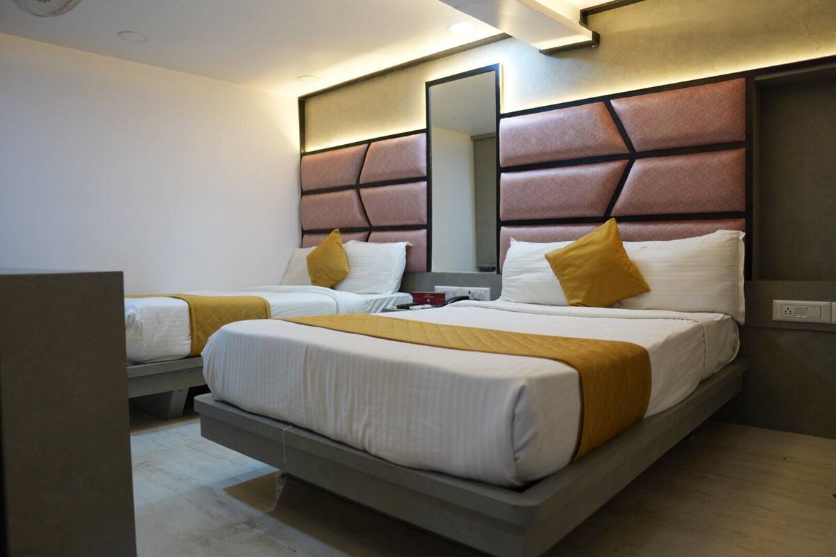 A hotel room with two beds, each with a headboard, white bedding, and a yellow throw blanket.