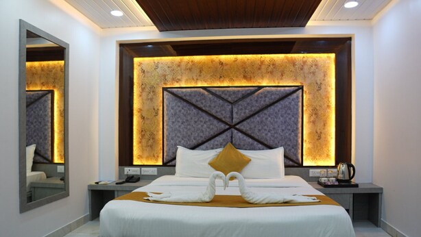 Een moderne hotelkamer met een groot bed, een hoofdbord met een geometrisch patroon en een spiegel aan de muur.