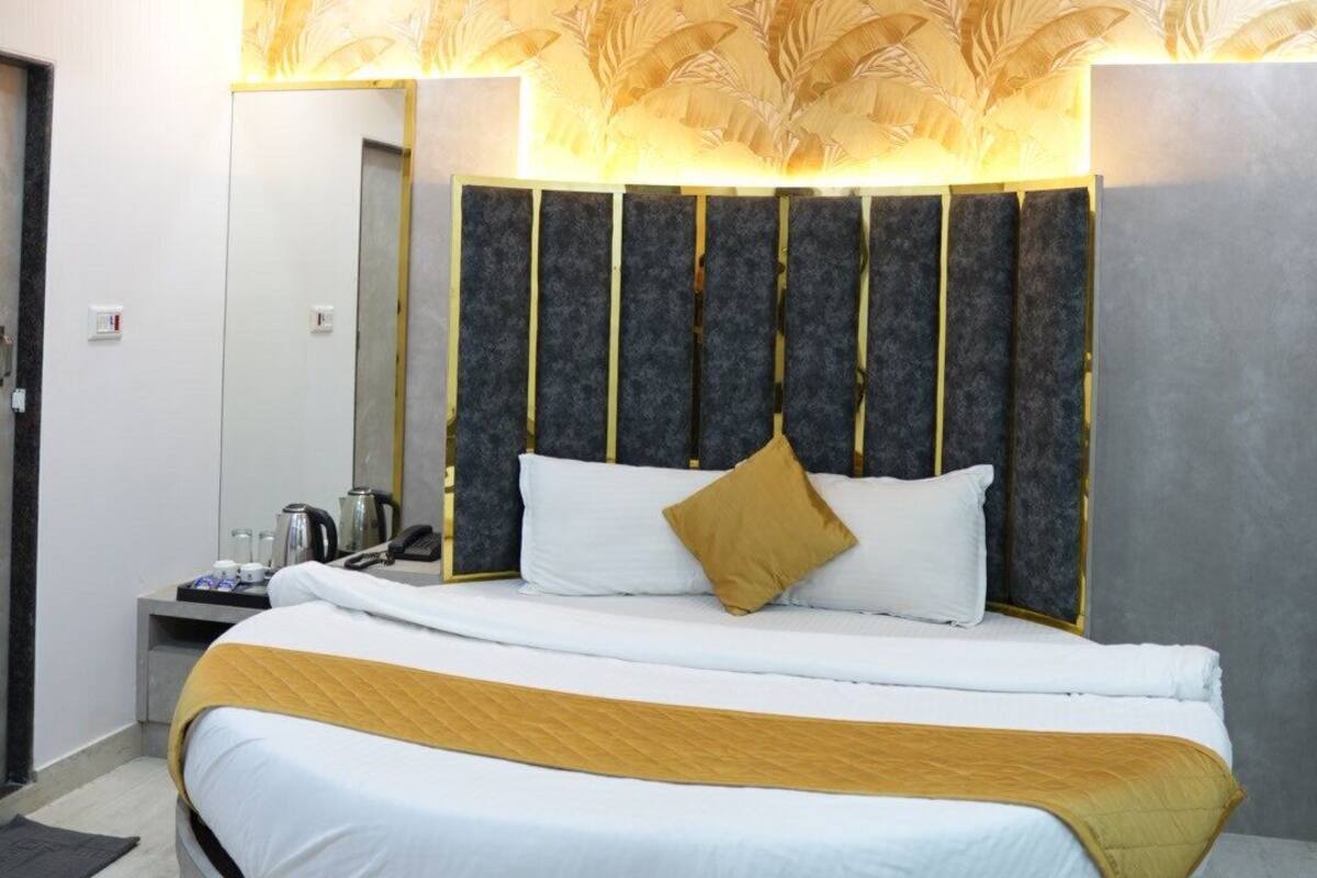 A modern hotel room with a round bed, a ceiling fan, a large mirror, and a decorative wall panel.