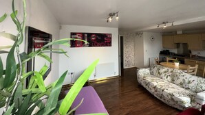 Ein Wohnzimmer mit einer Couch, einem Esstisch und einer Küchenzeile.