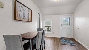 A dining area with a wooden table and grey chairs, a framed artwork on the wall, and a door leading to a balcony. - Sunny, Furnished  2 Bedroom Upper Apt Near Downtown Green Bay (Green Bay)