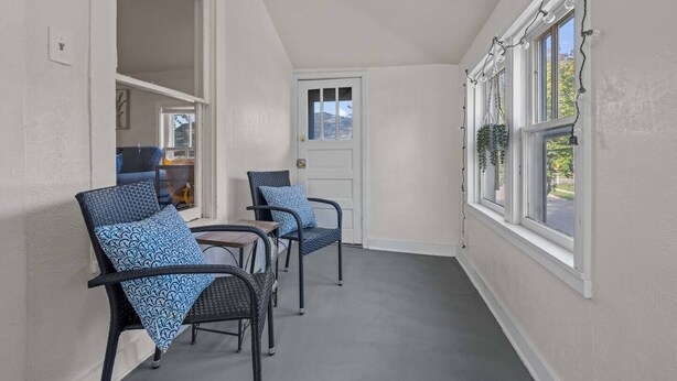 A narrow hallway with a door at the end, leading to a room with a view. There are three wicker chairs with blue cushions along the wall. - Sunny, Furnished  2 Bedroom Upper Apt Near Downtown Green Bay (Green Bay)