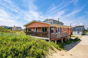 Una casa de playa con terraza de madera y porche cubierto.