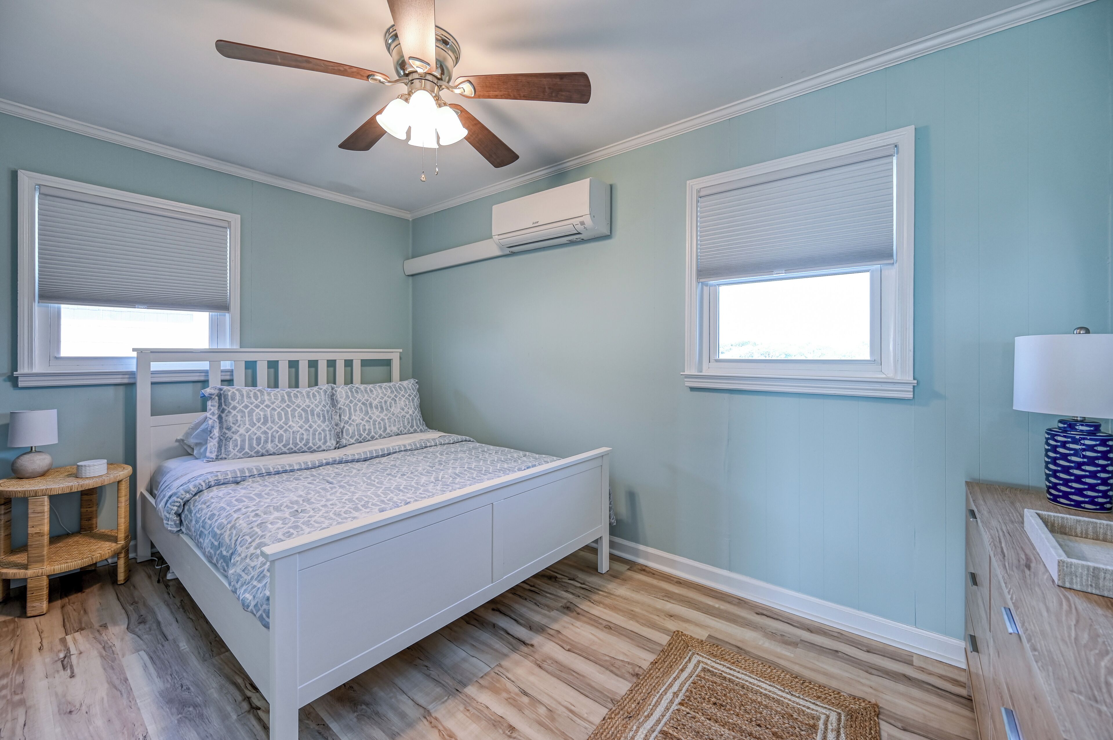 Un dormitorio con cama, ventilador de techo, aire acondicionado y ventana con persianas.