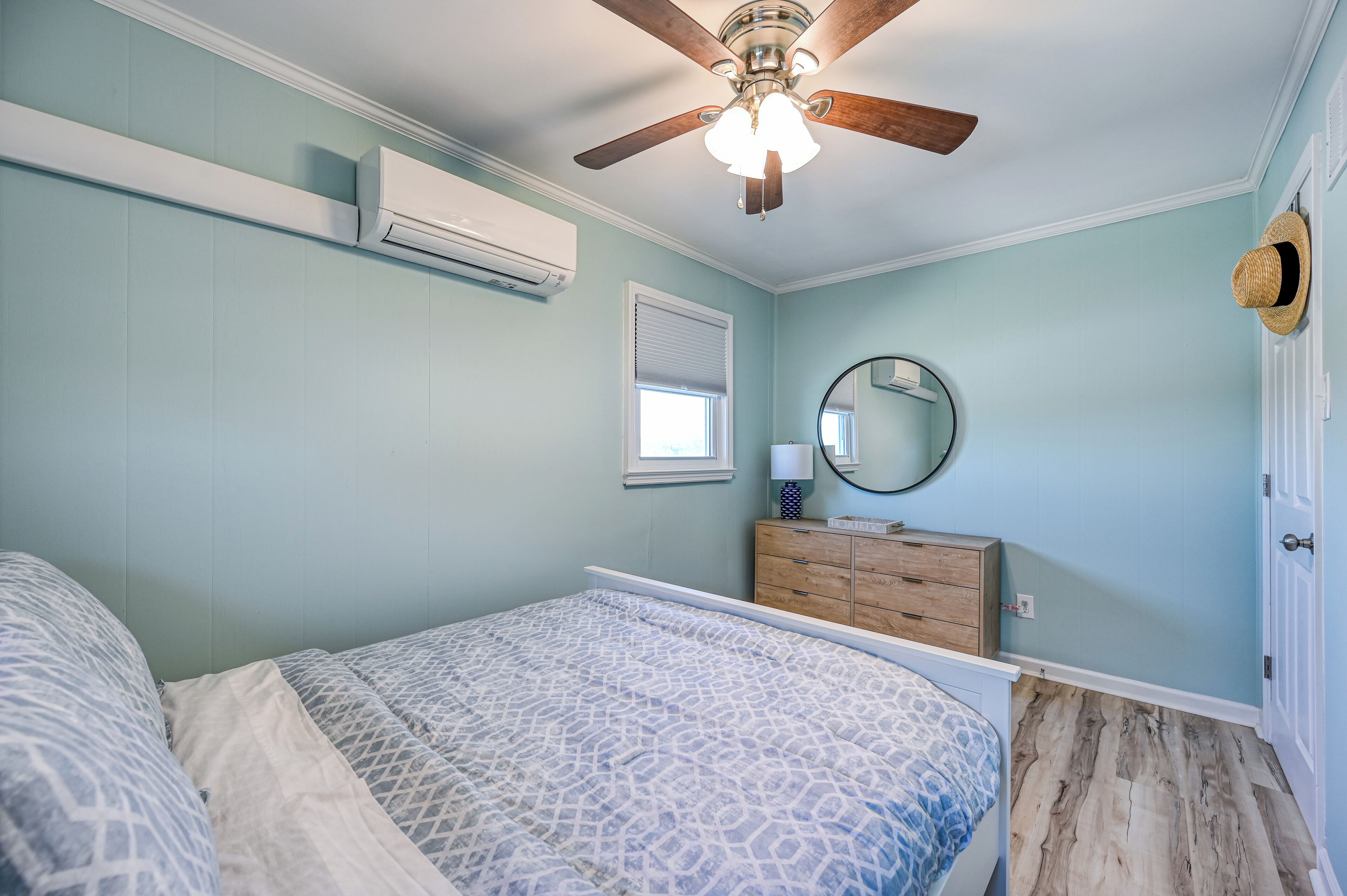 A bedroom with a bed, dresser, ceiling fan, and window.