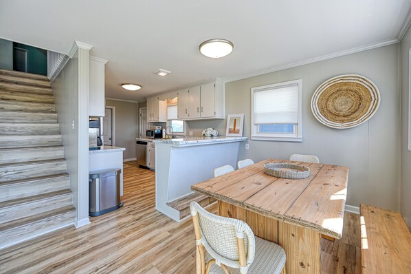 A kitchen with white cabinets, a wooden island, and a dining table with chairs.