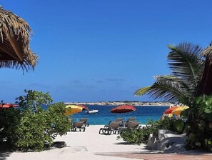 A beachside view with lounge chairs and umbrellas, a clear blue sky, and a calm sea.