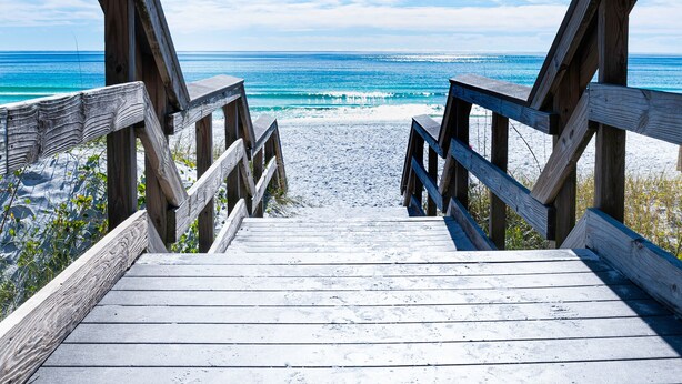 Un muelle de madera que conduce a una playa con vista clara al océano.