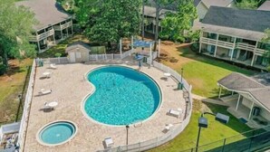 Una gran piscina con forma de riñón rodeada de sillones de descanso y una pequeña terraza.