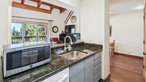 A modern kitchen with a built-in microwave, granite countertop, and stainless steel sink.