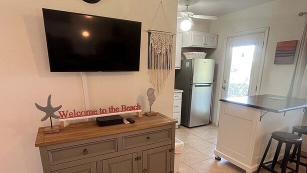 Una cucina con televisione, un bancone in legno e un cartello con la scritta 'Welcome to the Beach'.
