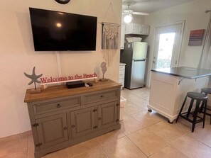 Une cuisine équipée d’un téléviseur, d’un comptoir en bois et d’une pancarte sur laquelle on peut lire « Bienvenue à la plage ».