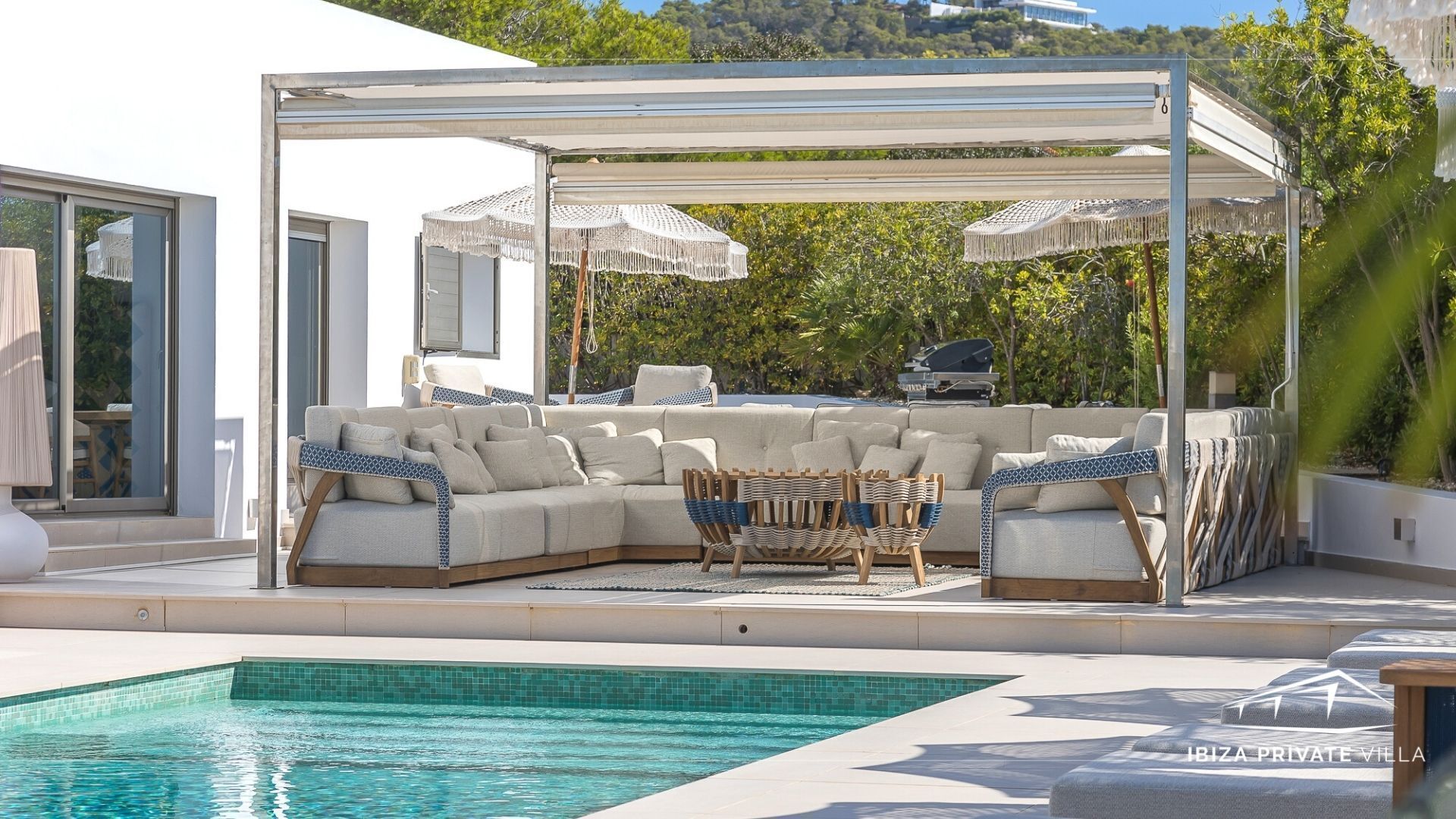 Zona de piscina con un área de descanso cubierta, una piscina y vistas del paisaje circundante.