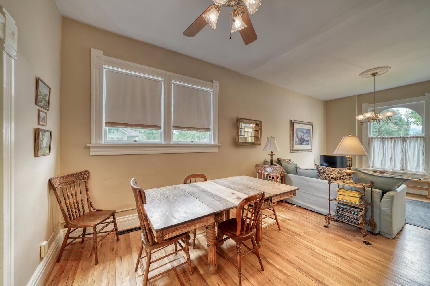A dining area with a wooden table and chairs, a sofa, and a lamp.