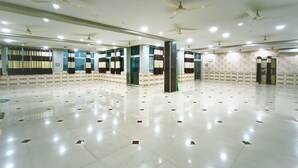 Un hall d’hôtel spacieux et bien éclairé, doté d’un sol ciré, de ventilateurs de plafond et d’un mur orné de motifs.
