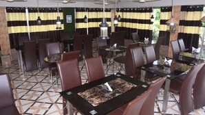 Un restaurant doté de nombreuses tables et chaises, de ventilateurs de plafond et de rideaux à rayures.