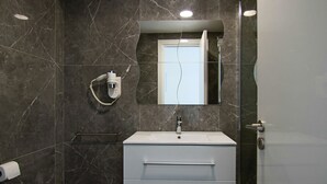 A bathroom with a white sink, dark marble walls, a mirror, and a towel rack. - Phaedrus Living Luxury Suite Nicosia 507 (Strovolos)