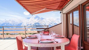 A round table with pink chairs and a red canopy, overlooking snow-capped mountains. - Olympic F8 by Interhome (Nendaz)