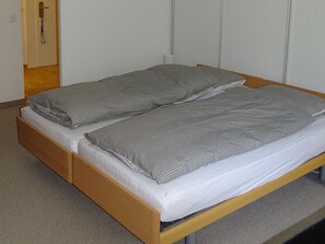 A single bed with a wooden frame and a mattress with a patterned cover.