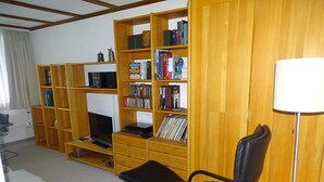 A living room with a fireplace, bookshelves, a television, a sofa, and a lamp. - Parkweg 9/602 Appartement/Fewo 2-Bettwohnung by Interhome (Engelberg)