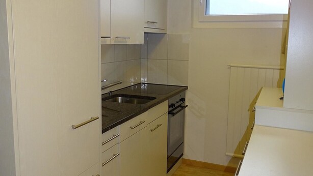 A compact kitchen with white cabinets, a black countertop, and a stainless steel sink. - Parkweg 9/602 Appartement/Fewo 2-Bettwohnung by Interhome (Engelberg)