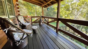 A wooden deck with two rocking chairs and a small table, overlooking a lush green landscape. - Grumpy Bear Cabin-Hot Tub-Pet Friendly (Murphy)