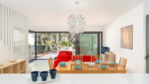 A modern dining area with a wooden table set for four, a red sofa, and a glass door leading to an outdoor patio. - 4 Bedroom Modern House, Llafranc, Costa Brava (Llafranc)