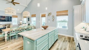 A spacious kitchen with a large island, pendant lights, and a ceiling fan. - Sweet & Salty - Hot Tub, Across from Jetty, Best Ship Watching! (Surfside Beach)
