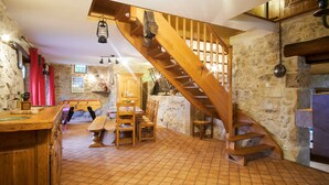 A rustic interior with a wooden staircase, stone walls, a wooden bar, and a dining area. - Holiday Accommodation "Maison de pierre" with beautiful view (Saint-Gervais)