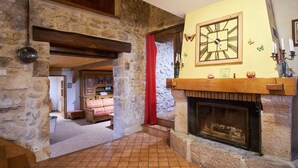 A stone-floored room with a fireplace, wooden beams, and a red curtain. - Holiday Accommodation "Maison de pierre" with beautiful view (Saint-Gervais)