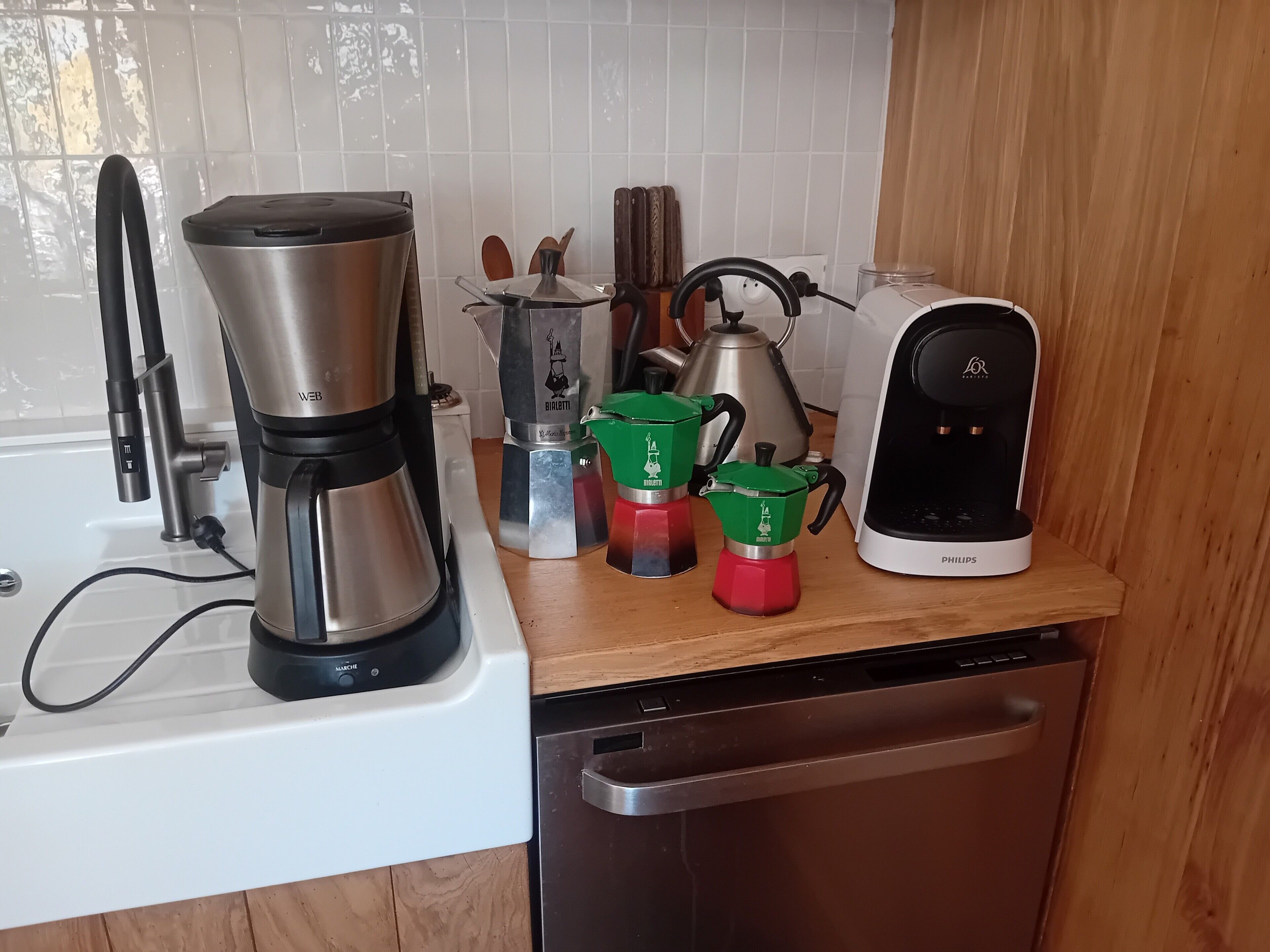 Keittiössä on kahvinkeitin, vedenkeitin, kahvipannu ja espressokone työtasolla.